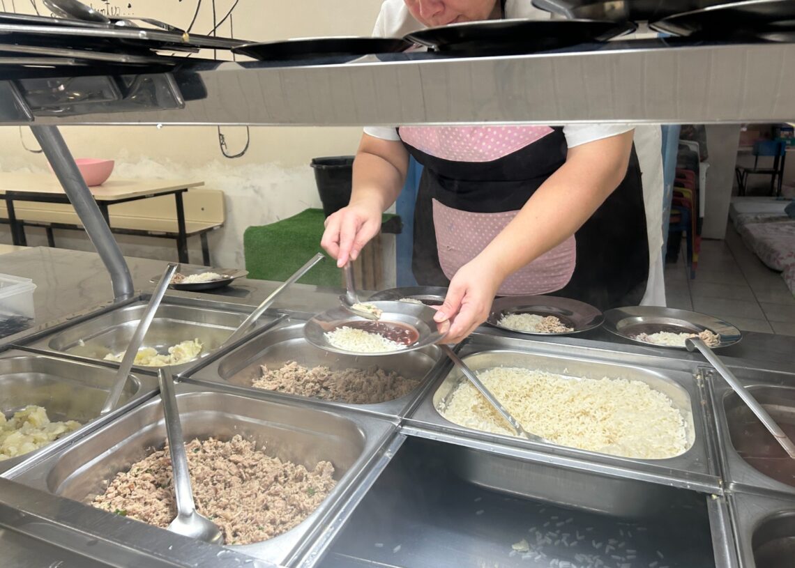 Funcionários de cozinha servem os alimentos em porções iguais às crianças